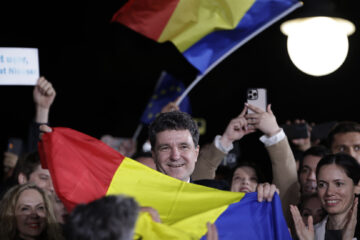 Nicusor Dan houdt om een menigte lachend een Roemeense vlag vast