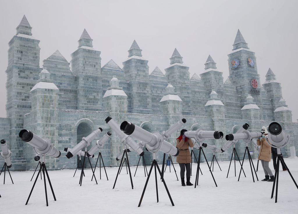 Bezoekers van het International Ice and Snow Festival turen door telescopen in de Chinese stad Harbin. – © Kim Kyung-Hoon / Reuters