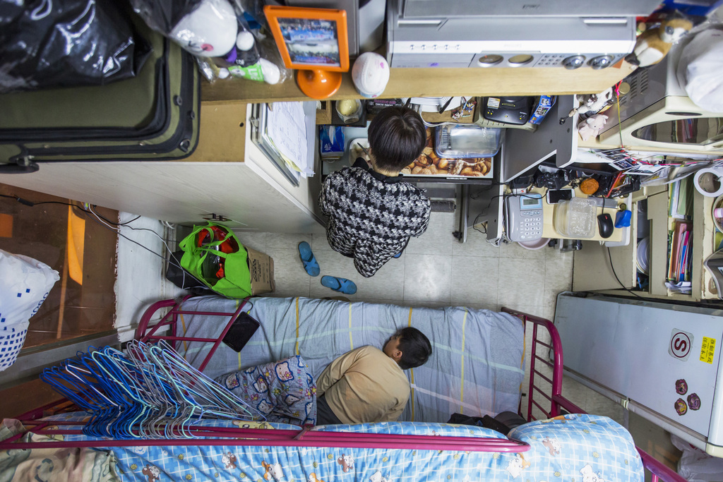 Een vrouw met haar zoontje in hun piepkleine flat in Hongkong, waarvoor ze 500 dollar huur betaalt. – © Tyrone Siu / Reuters