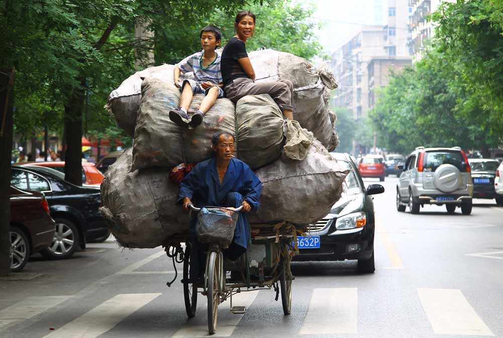 Afvalsorteerders in Shanghai en in Beijing (onder) op hun kenmerkende driewielers. – © Getty