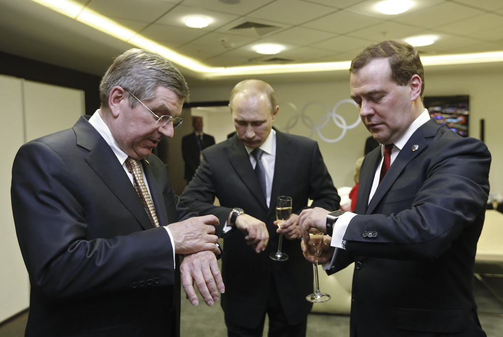 Vladimir Poetin, Dmitry Medvedev en IOC-voorzitter Thomas Bach zetten hun horloges gelijk voor de sluitingsceremonie van de Olympische Winterspelen in Sotsji. – © Dmitry Astakhov / Reuters