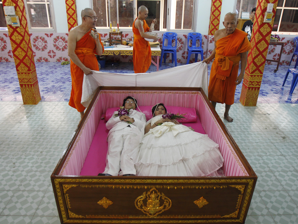 Huwelijksceremonie op Valentijnsdag in de provincie Nonthaburi, niet ver van Bangkok. De koppels brengen korte tijd door in een luxueuze tweepersoonskist. Het ritueel in de Wat Takien-tempel zuivert de jonge gelukszoekers van kwade invloeden. – © Chaiw