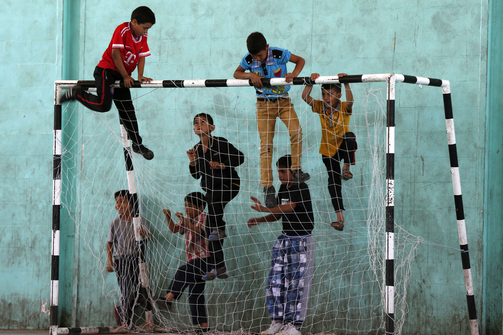 Syrische en Palestijnse kinderen klimmen op een doel voor de start van een wedstrijd in het vluchtelingenkamp Al-Baqaa. – © Muhammad Hamed / Reuters