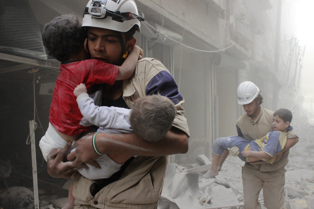 Reddingswerkers dragen kinderen weg na een luchtaanval van (vermoedelijk) troepen van de Syrische president Assad. – © Sultan Kitaz / Reuters 