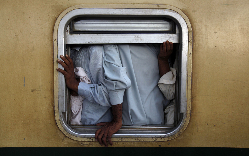 Mannen in een trein op weg naar huis voor Eid el-Fitr (het Suikerfeest), op een station in Karachi. – © Akhtar Soomro / Reuters