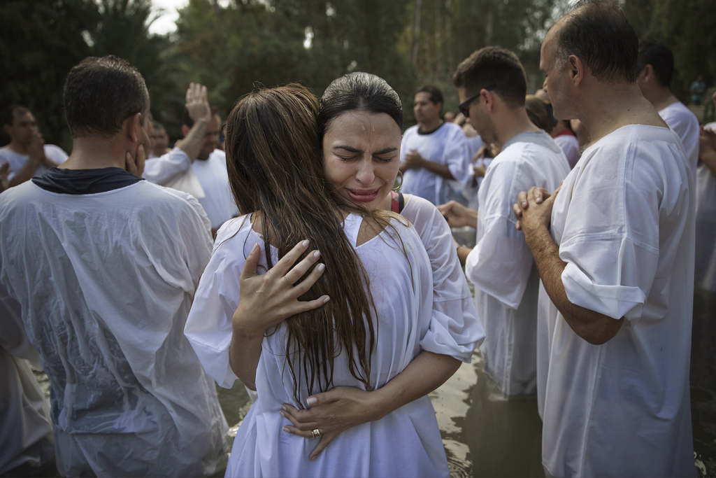 Christelijke pelgrims uit Brazilië omhelzen elkaar nadat ze zijn gedoopt in het water van de Jordaan op – naar verluidt – dezelfde plek waar Jezus werd gedoopt in de buurt van de Israëlische stad Tiberias. Foto: Finbarr O'Reilly/Reuters